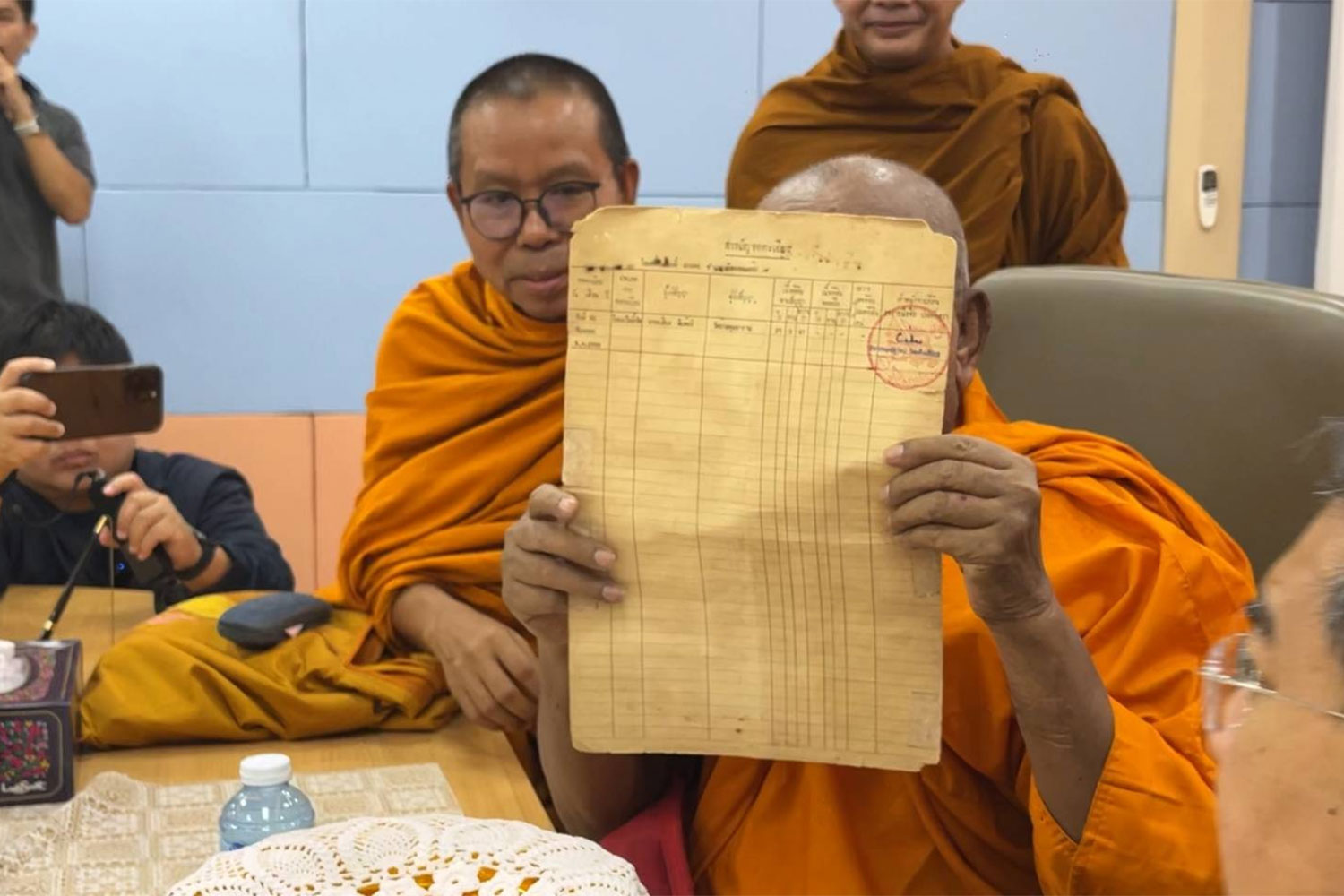 Phra Kru Adulyasananithet, abbot of Wat Pa Adulyaram in Khon Kaen's Muang district, shows a land title deed to reporters and people who gather at the Khon Kaen Land Office on Wednesday. (Photo: Chakkrapan Natanri)