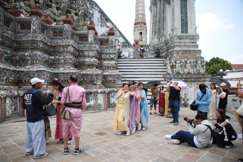 Tourists in traditional Thai costumes rented from shops pose for photos at Wat Arun, or the Temple of Dawn, in Bangkok on April 27. (Photo: Varuth Hirunyatheb)