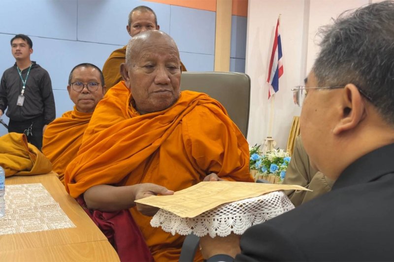 Phra Kru Adulyasananithet, the abbot of Wat Pa Adulyaram in Muang district of Khon Kaen, receives a land title deed after ownership details were amended to list the forest temple as its owner, from a land official on Wednesday. (Photo: Chakkrapan Natanri)