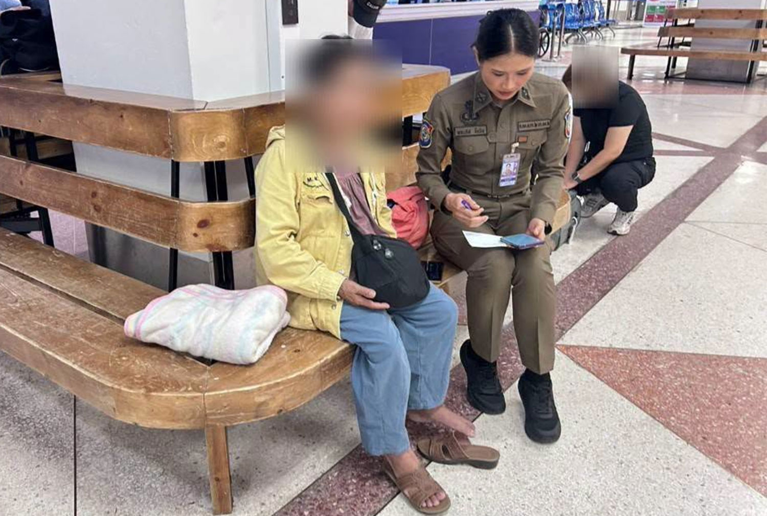 A tourist policewoman speaks to Ms Ipo, a 66-year-old tribal woman from Lampang as the latter travel to Chiang Mai airport to meet her pilot boyfriend she fell in love online. (Photo: Chiang Mai Tourist Police)