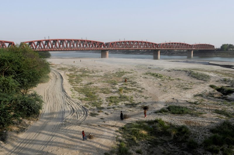 People walk on the dry riverbed of the Indus River in Hyderabad, Pakistan in April 2025. The Indus has been drying out in Pakistan due to a combination of heavy infrastructure diversion, upstream geopolitical tensions and climate change. (Photo: Reuters)