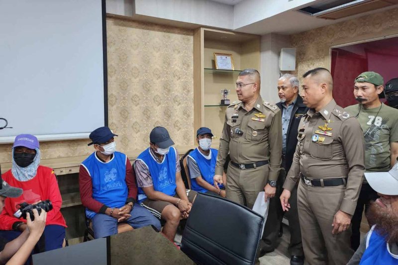 Deputy national police chief Pol Gen Samran Nualma (right) looks at suspects in the ID card case at the Surat Thani police headquarters on Thursday. (Police photo)