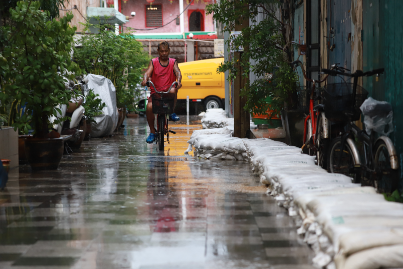 A man rides a bicycle down a rain soaked alley in Bangkok. (photo: Bangkok Post)