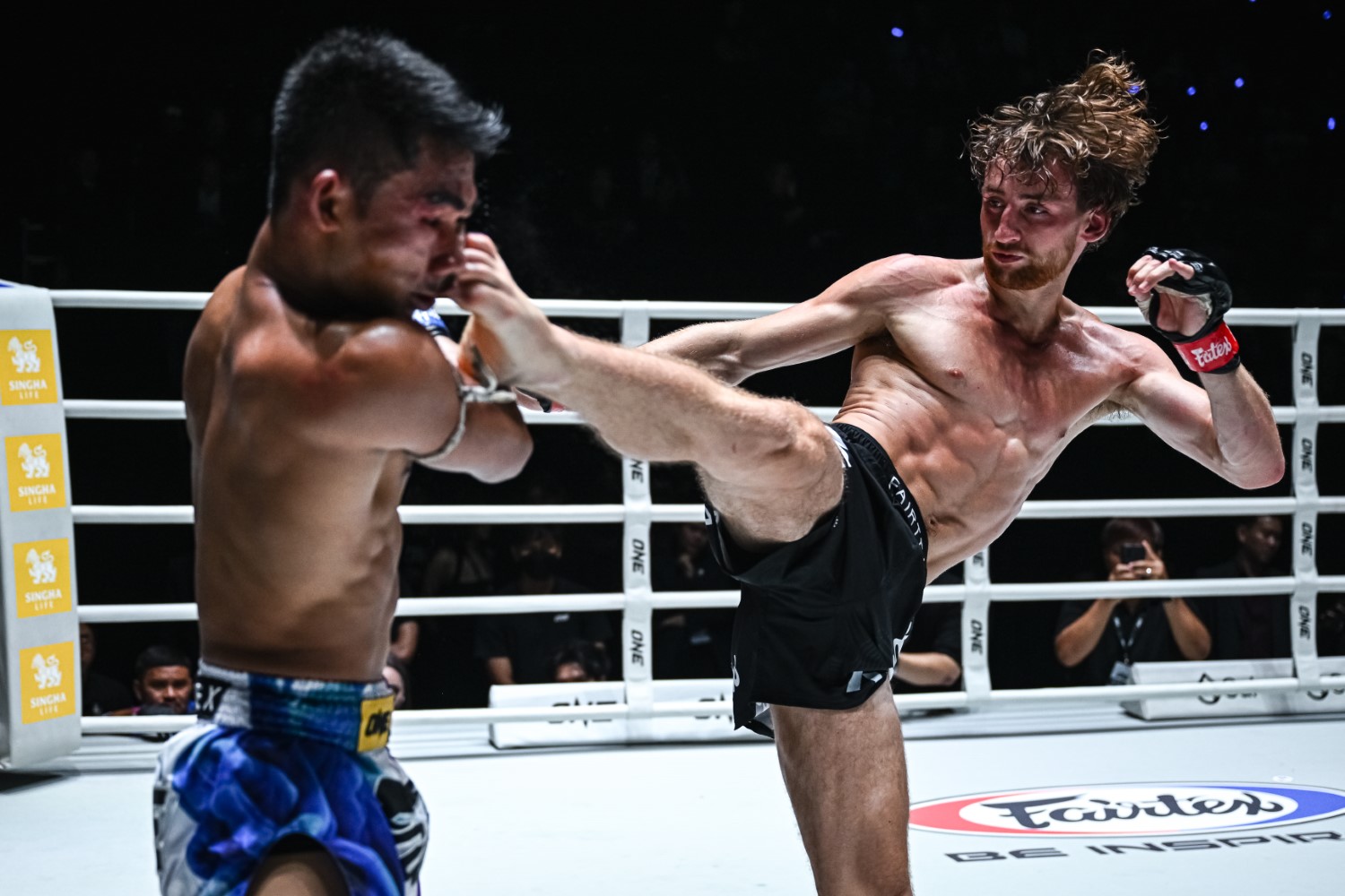 Freddie Haggerty attacks Rungruanglek TN Muaythai with a high kick during their strawweight Muay Thai bout at Lumpinee Stadium