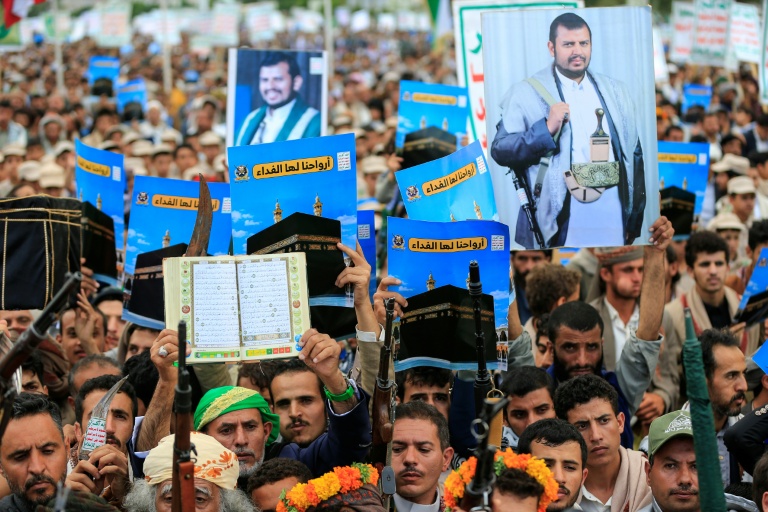 Supporters of the Houthis brandish weapons and hold up placards showing the Kaaba and reading "For it, we willingly offer our souls" during a protest against Saudi Arabia's recent accusation that the Houthis fired at the holy city of Mecca. (Photo: AFP)