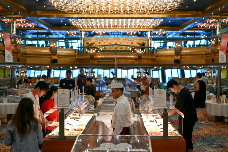 Athletes pick up food at a buffet in a dining room on the Costa Serena cruise ship anchored off Nagoya, Japan. (Photo: AFP)