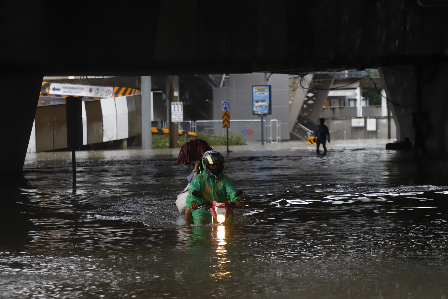 A motorcyclist with a passenger navigates high floodwaters in Lat Phrao district in Bangkok on Saturday. (Photo: 	Nutthawat Wichieanbut)