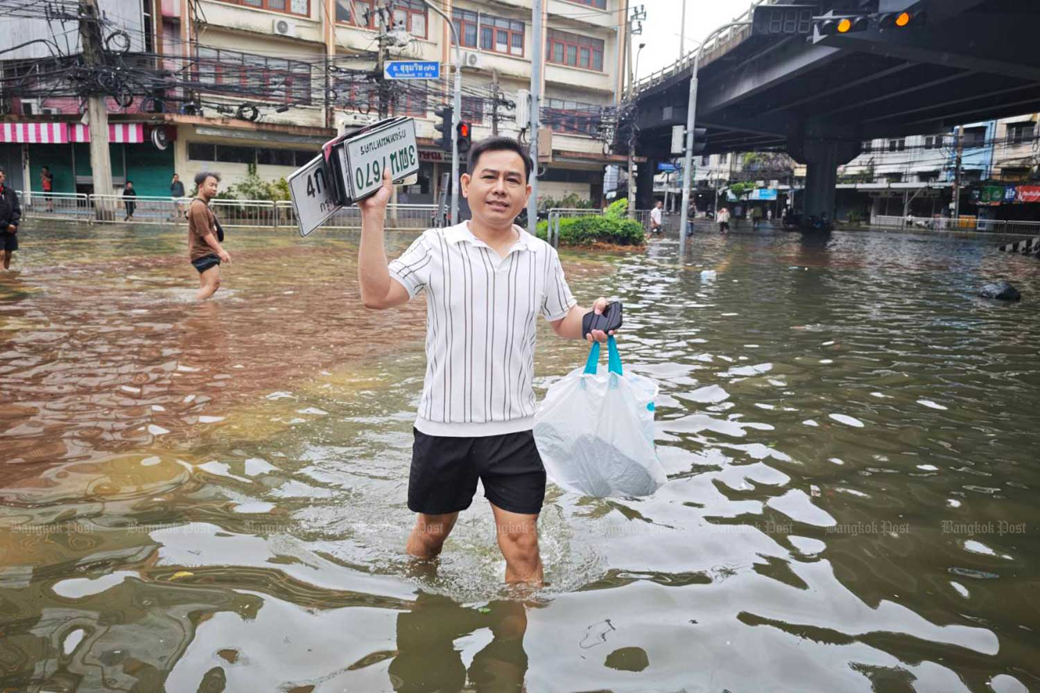 A man collects licence plates for owners to recover later, at Khlong Tan intersection.