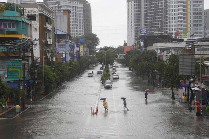 Pedestrians cross Lat Phrao Road in Bangkok in the rain on Saturday. (photo: Nutthawat Wichieanbut