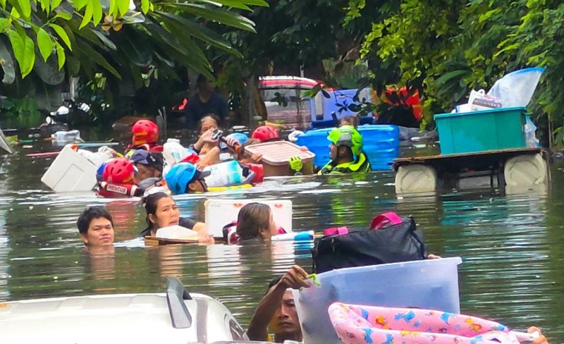 Residents make their way through neck-high floodwater as Poh Teck Tung Foundation rescuers evacuate stranded and vulnerable people from the Rom Klao public housing estate in Lat Krabang district on Sunday. (Photo: Poh Teck Tung Foundation)