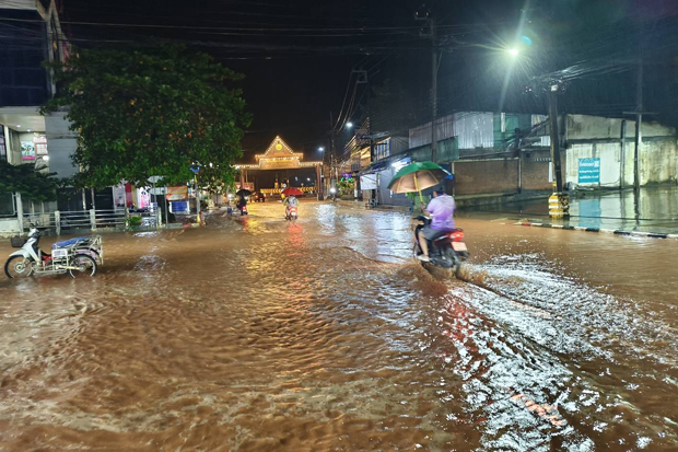 A motorcyclist navigates a flooded road in Thong Pha Phum township in Kanchanaburi on Sunday night, as the level of the Kwai Noi River continued to rise. (Photo: Piyarach Chongchareon)