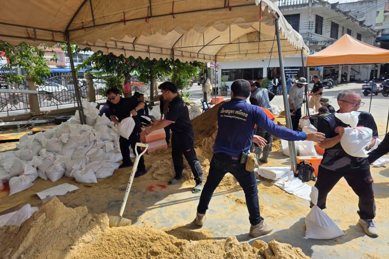 Samut Songkhram municipal workers fill sandbags as they build a wall against the threat of flooding by the rising Mae Klong River, in Muang district in Samut Songkhram on Tuesday. (Photo: Samut Songkhram municipality)