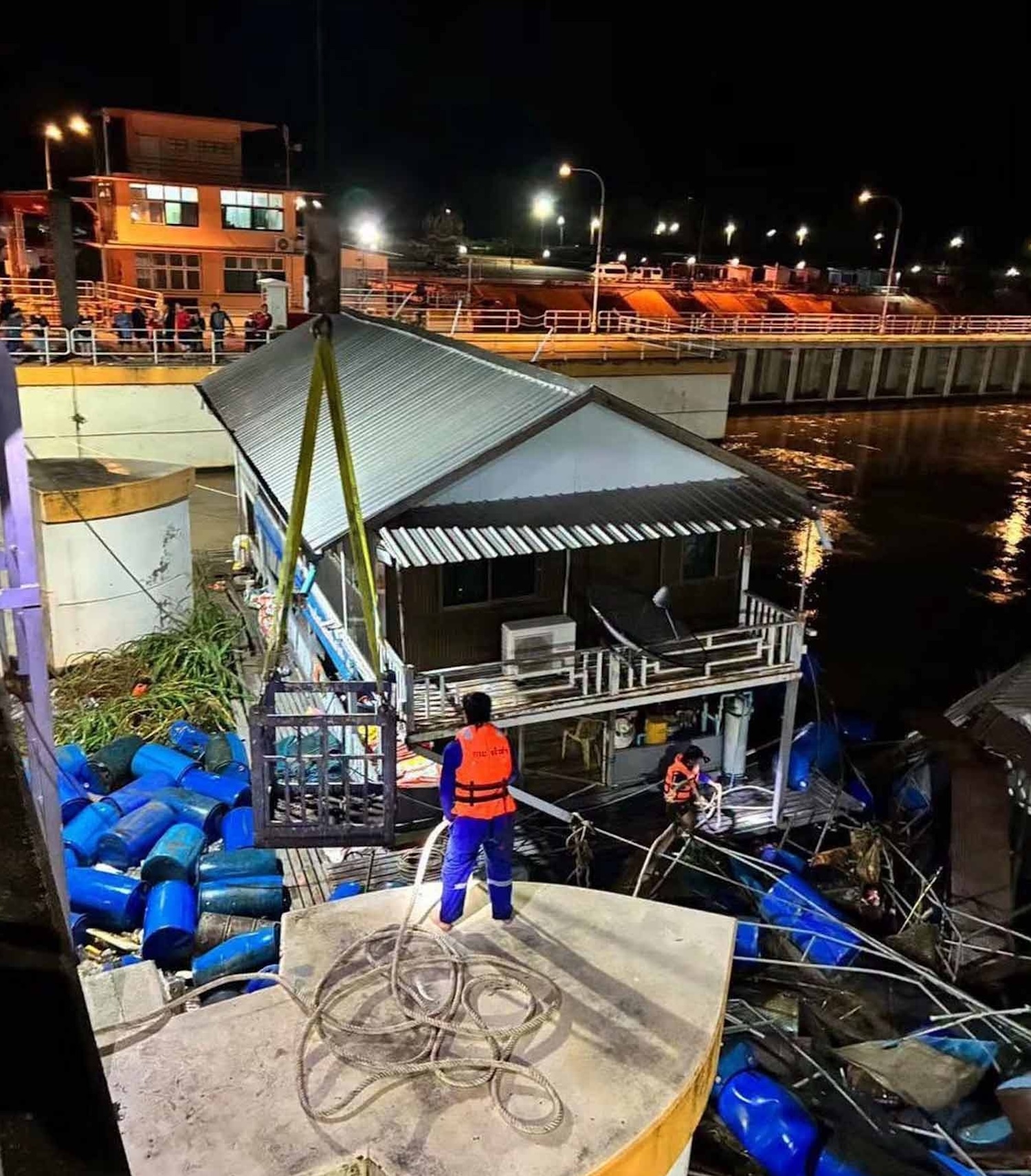 Workers try to secure fish cages and floats at the dam site on Tuesday night. (Photos: Piyarach Chongcharoen)