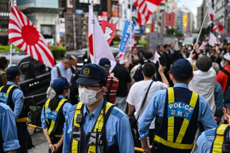 Japanese police monitor a rally by nationalists against changes to the country’s immigration law. Foreign residents wishing to stay in Japan permanently will now have to prove their annual income is above average. (Photo: AFP)