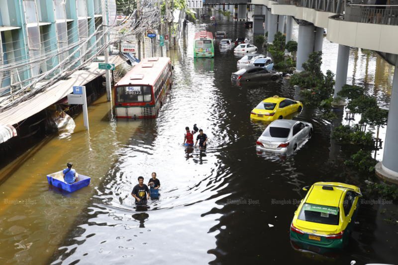 People walk through floodwaters in front of Bang Kapi Market in Bangkok on Sept 29. Floods in Bangkok have prompted tourists to cancel their hotel bookings over the past few days. (Photo: Nutthawat Wichieanbut)
