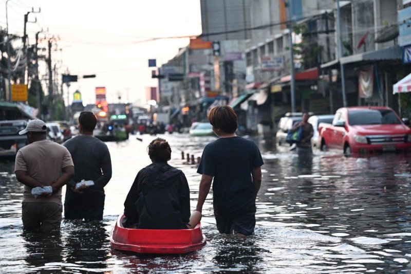 People wade through floodwaters in Rom Klao area of Bangkok's Lat Krabang district on Friday. The government has warned residents in the Central Plains and areas along the Chao Phraya River to prepare for heavy rain expected on Oct 11-14. (Photo: Bangkok Metropolitan Administration)