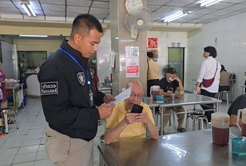 A cybercrime police officer reads out the charges in an arrest warrant for crime victims’ rights activist Atchariya Ruengrattanapong (in yellow shirt), who was arrested on Saturday. (Photo supplied/Wassayos Ngamkham)