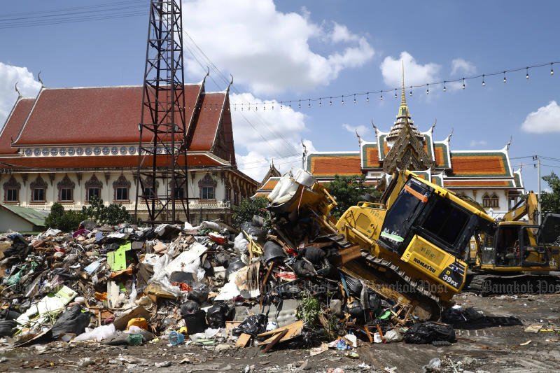 A tractor works on a mountain of rubbish at Wat Bueng Thonglang in Bang Kapi district on Wednesday as the temple opens a free garbage disposal point to help reduce the amount of waste left in the community during the post-flood recovery period in Bangkok. (Photo: Nutthawat Wichieanbut)