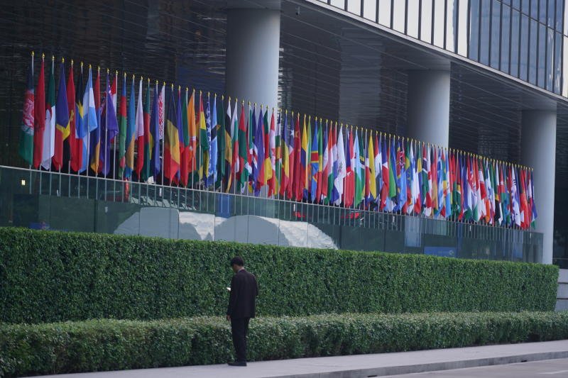 A man stands in front of the flags of International Monetary Fund and World Bank members, at Queen Sirikit National Convention Center on Thursday. (Photo: Wisuttipong Rodpai)