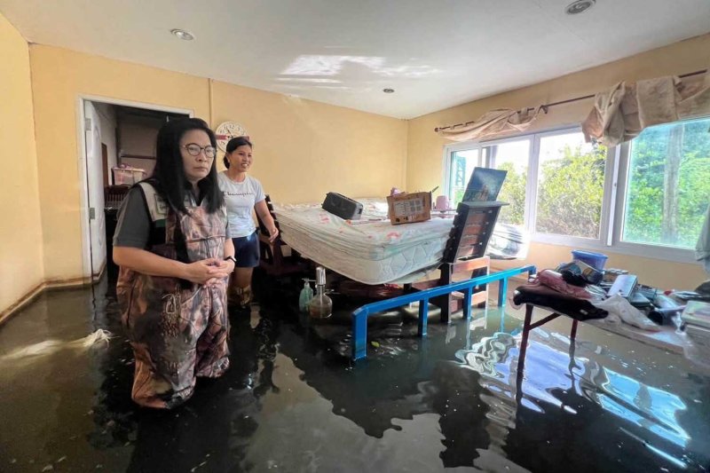 A local administrative official, left, visits a flooded house in Chachoengsao province on Sunday. (Photo: PR Department)