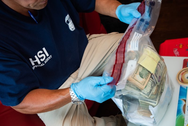 A US Homeland Security Investigations officer in Honolulu inspects seized banknotes as part of a money laundering investigating into illegal gambling businesses in Hawaii in November 2019. (Photo: usicegov via Wikimedia Commons)