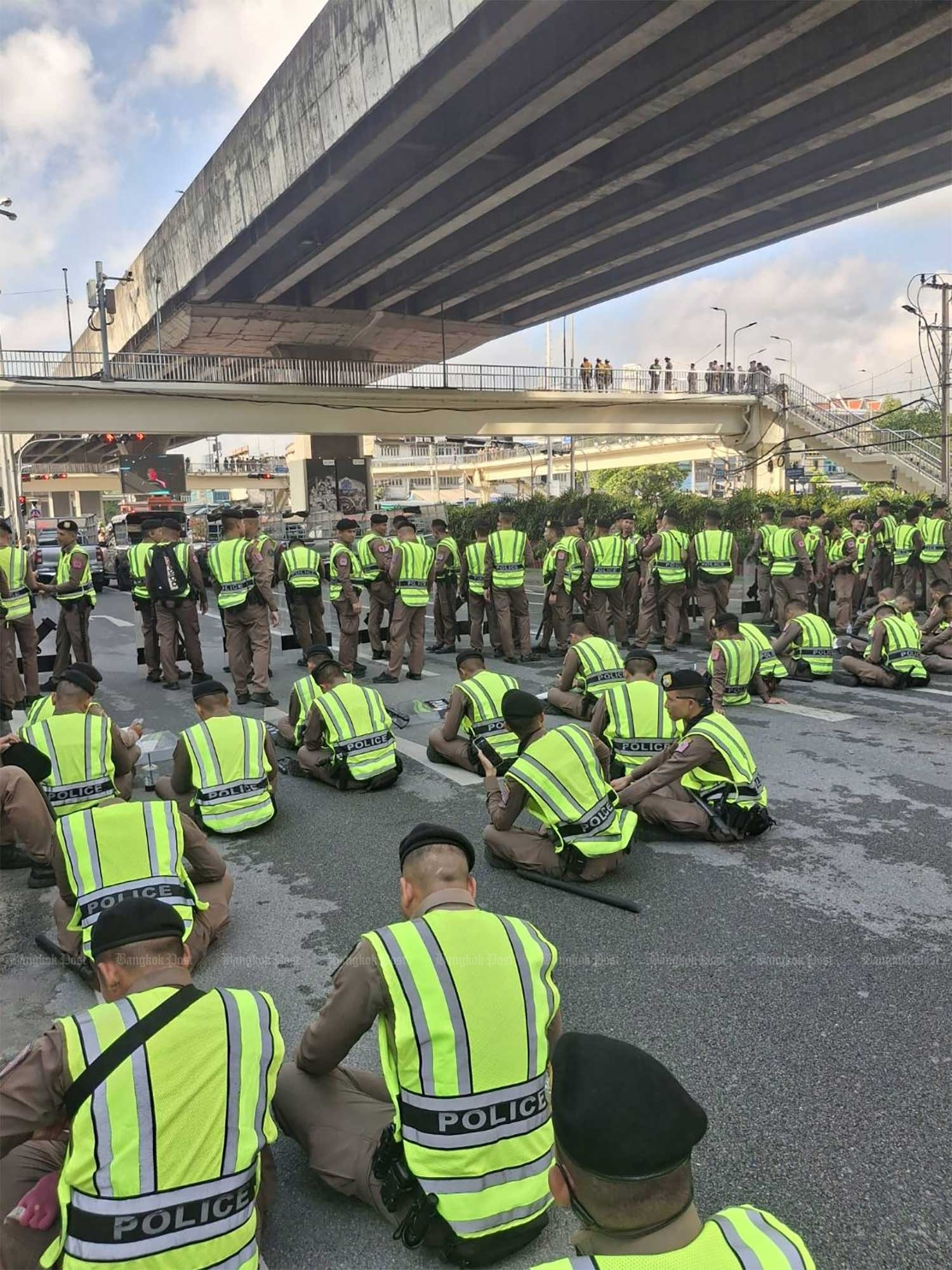 Police with batons await the arrival of demonstrators. (Photo: Charoen Kittikanya)