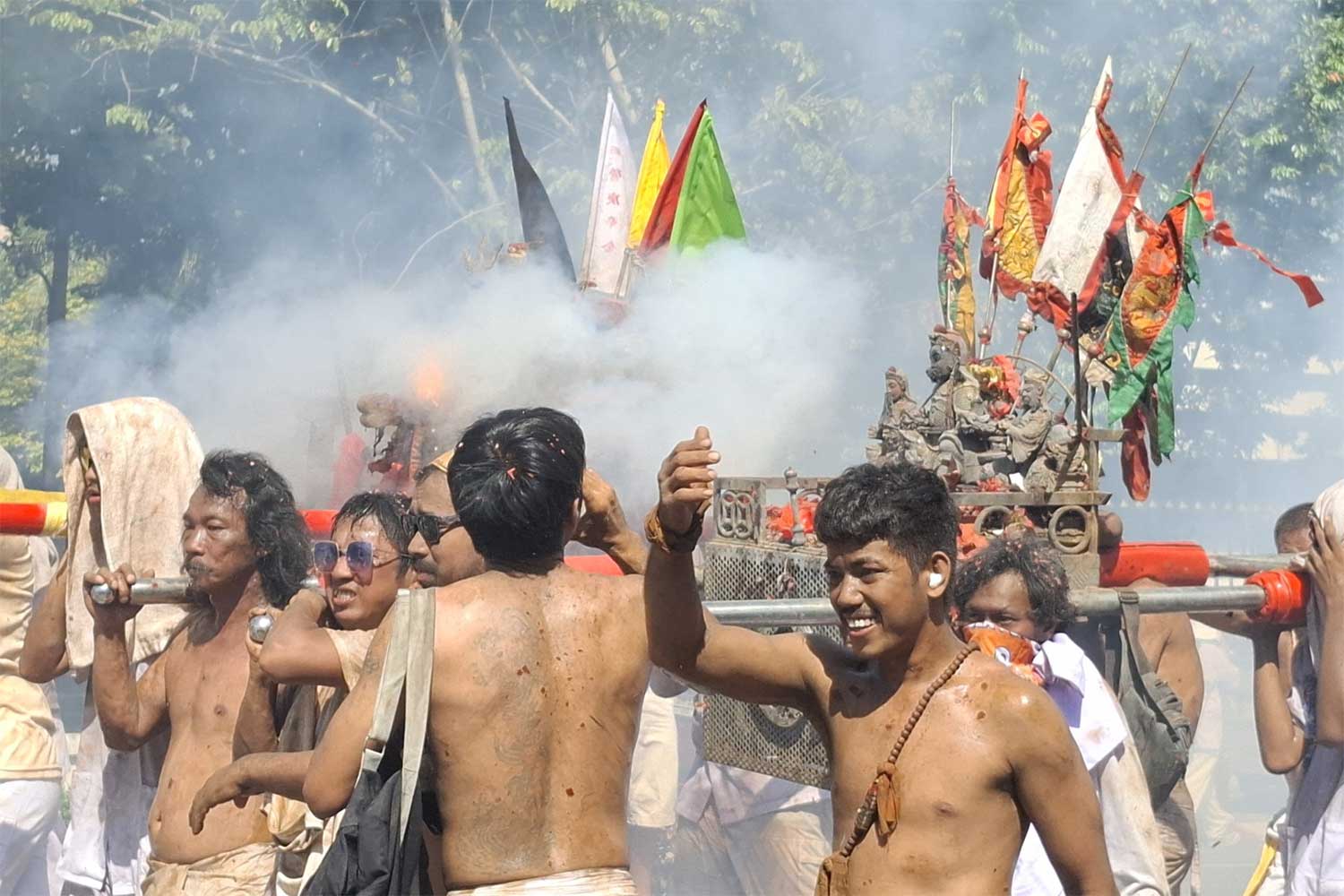 Believers parade deity images as firecrackers explode.