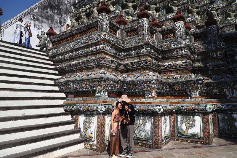 Tourists, one of them dressing in traditional Thai attire, pose for a photo at Wan Arun, also known as the Temple of Dawn, on Jan 7, 2025. (Photo: Nutthawat Wichieanbut)