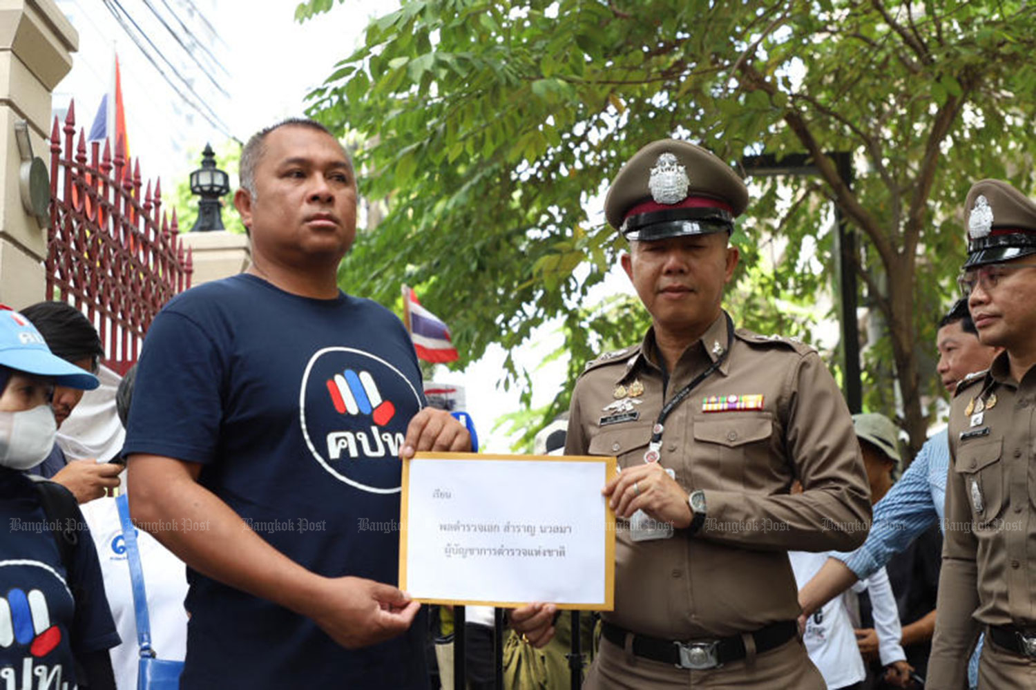Pichit Chaimongkol, a leader of the Network of Students and People for Reform of Thailand, submit a petition to national police chief Pol Gen Samran Nualma via Pol Lt Col Sucharit Chothapthim, deputy superintendent of the police information division on Wednesday. (Photo: Pornprom Satrabhaya)