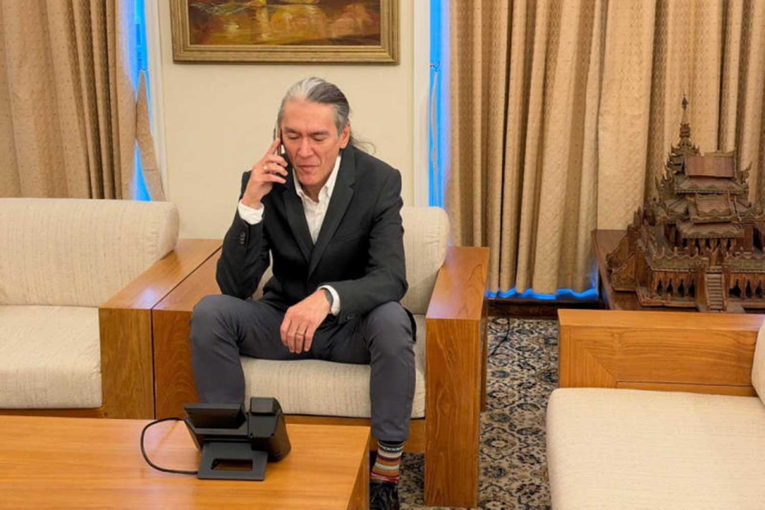 Aung San Suu Kyi's son, Kim Aris, talks on the phone with his mother, Myanmar's former leader, who is in Naypyitaw, Myanmar, from Myanmar's embassy in London, Britain, October 22, 2026. Myanmar Presidential Spokesperson/Handout via REUTERS.
