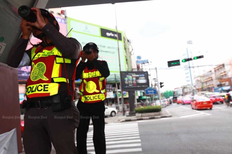 Traffic police take photos of drivers using mobile phones while behind the wheel, at Khlong Tan intersection in Bangkok. (Photo: Bangkok Post)