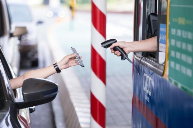 A motorist uses his smartphone to pay the highway toll via Alipay, Alibaba's online payment service, at Pengbu toll station in Zhejiang, China. Alibaba and WeChat have a lock on Thailand's mobile third-party payment services for Chinese travellers.