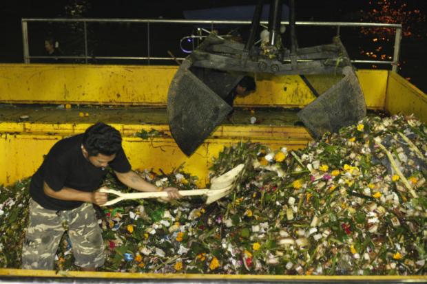 A Bangkok Metropolitan Administration worker uses a shovel to scoop rubbish collected from city waterways following the Loy Krathong festival into a garbage grinder stationed near a pier in Bangkok Noi district on Monday night. Pornprom Satrabhaya