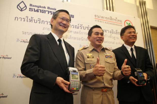 Finance permanent secretary Somchai Sujjapongse (centre), BBL president Chartsiri Sophonpanich (left) and KBank president Predee Daochai display EDC terminals. SEKSAN ROJJANAMETAKUN