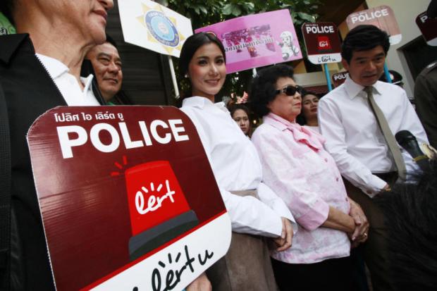Celebrities Primrada 'Chacha' Detudom, centre, and Wasu 'Jip' Saengsingkaeo, far right, attend the police launch of a new mobile phone app 'Police i Lert u,' which allows people to directly contact officers in case of an emergency over the New Year holiday. Pornprom Satrabhaya
