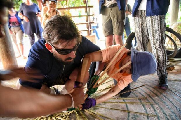 A villager helps a visually impaired visitor make a chicken coop in Phayao province.