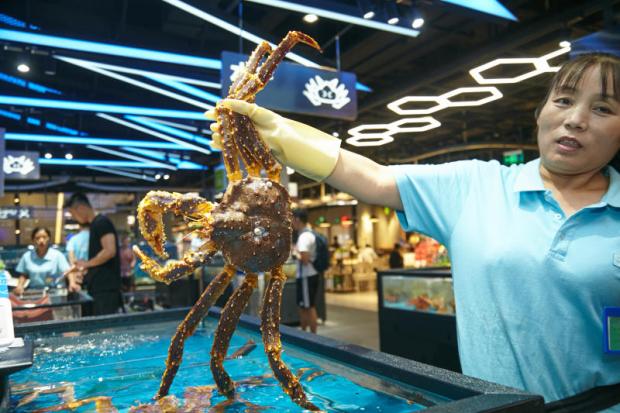 A vendor shows a live lobster. Customers can dine at the supermarket and take care of the bill using Alipay.