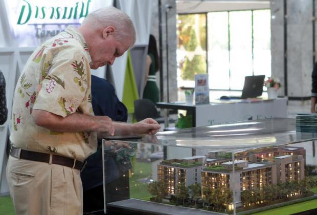 A man looks at a model of a low-rise condominium at a housing fair. TAWATCHAI KEMGUMNERD