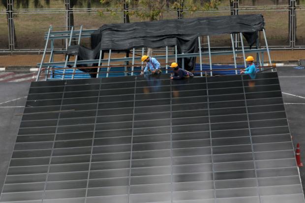 Workers are installing solar panels as roofs in parking lots. Thailand needs recycling facilities to support widespread use of solar panels. Chanat Katanyu