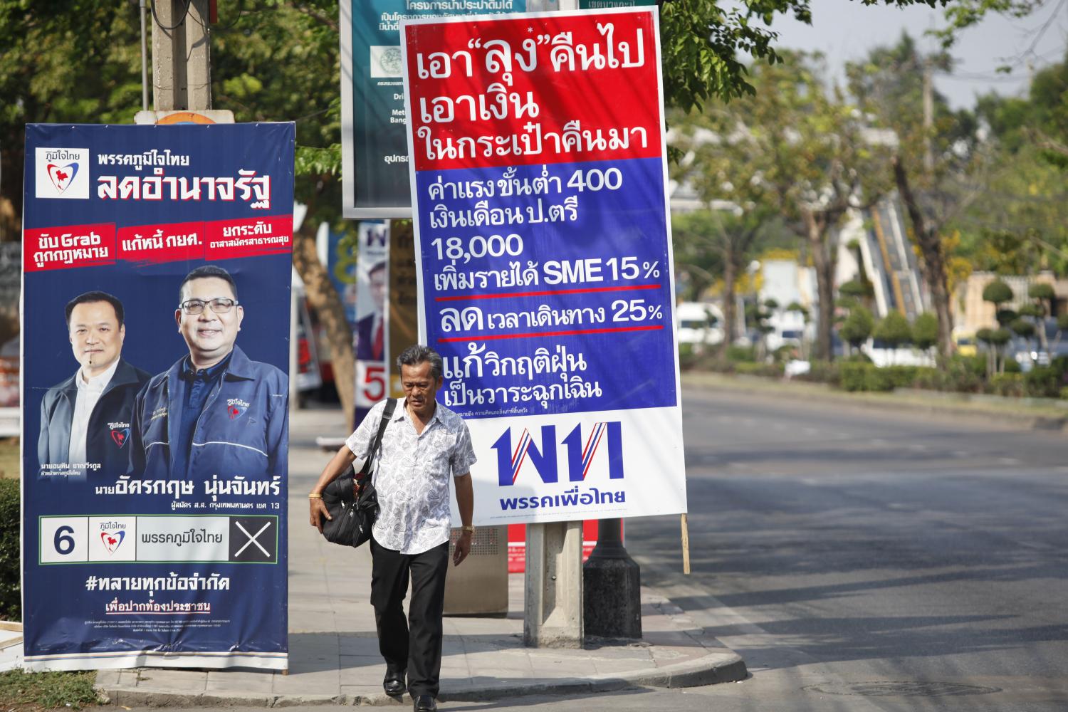 A man walks past a signboard listing Pheu Thai Party policies during the election campaign in March. (Photo by Varuth Hirunyathep) A man walks past a signboard listing Pheu Thai Party policies during the election campaign in March. (Photo by Varuth Hirunyathep)