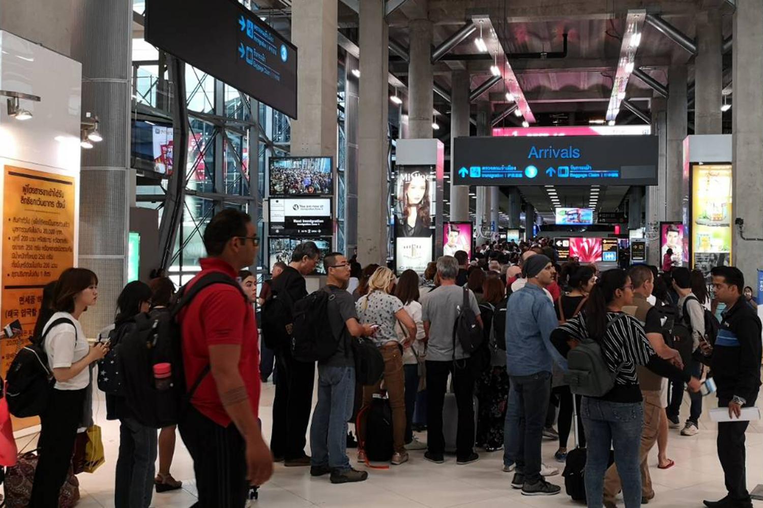 Tourists queue up in lengthy lines for immigration checks at Suvarnabhumi airport. (Bangkok Post photo)