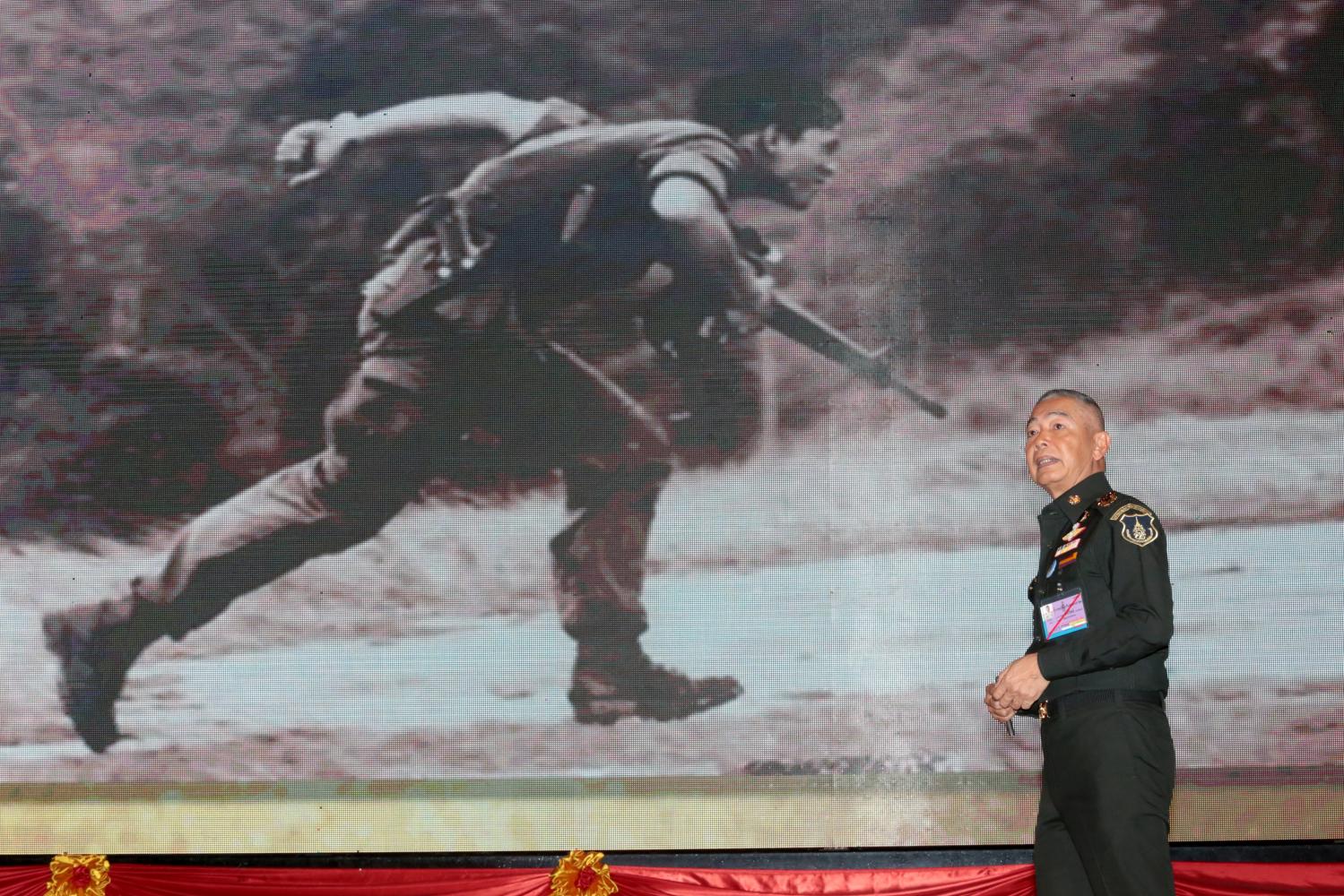 Army chief Gen Apirat Kongsompong describes how His Majesty the King fought against communists in Loei province in 1976, during a special lecture on national security at the Royal Thai Army Headquarters in Bangkok yesterday. Illustrating the lecture was a picture of the then-Crown Prince on the Loei battlefield. (Photo by Chanat Katanyu)