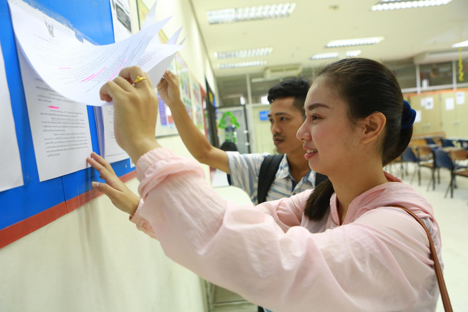 Job applicants read details of qualifications required by hotel and casino operators in Macao at the Labour Ministry which has offered them an opportunity to work abroad. (Photo by Somchai Poomlard)