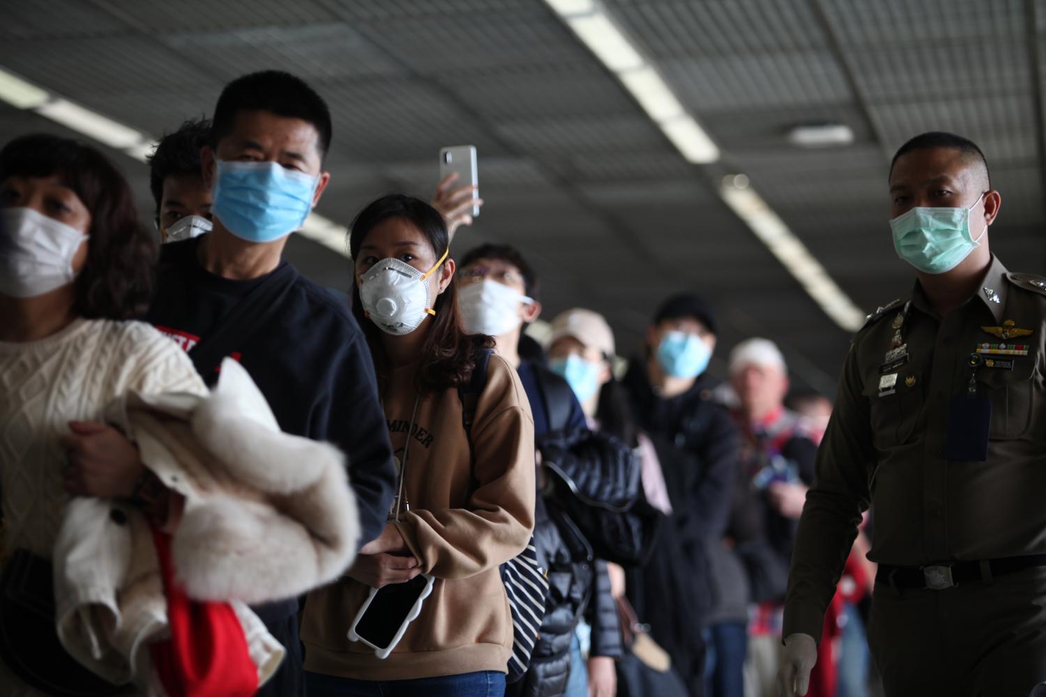 Initial check: Passengers arriving from China stand in a long queue as they wait to walk through a thermal scanner at Don Mueang Airport, which is intensifying the screening of passengers by checking them for signs of fever.