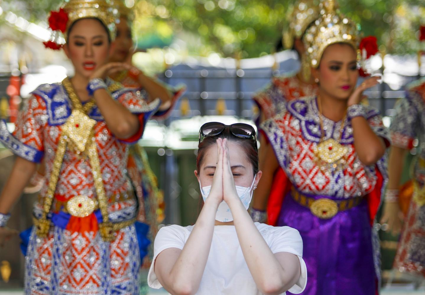 A Chinese tourist at the Erawan shrine at Ratchaprasong intersection prays while wearing a face mask. (Photo by Pattarapong Chatpattarasill)