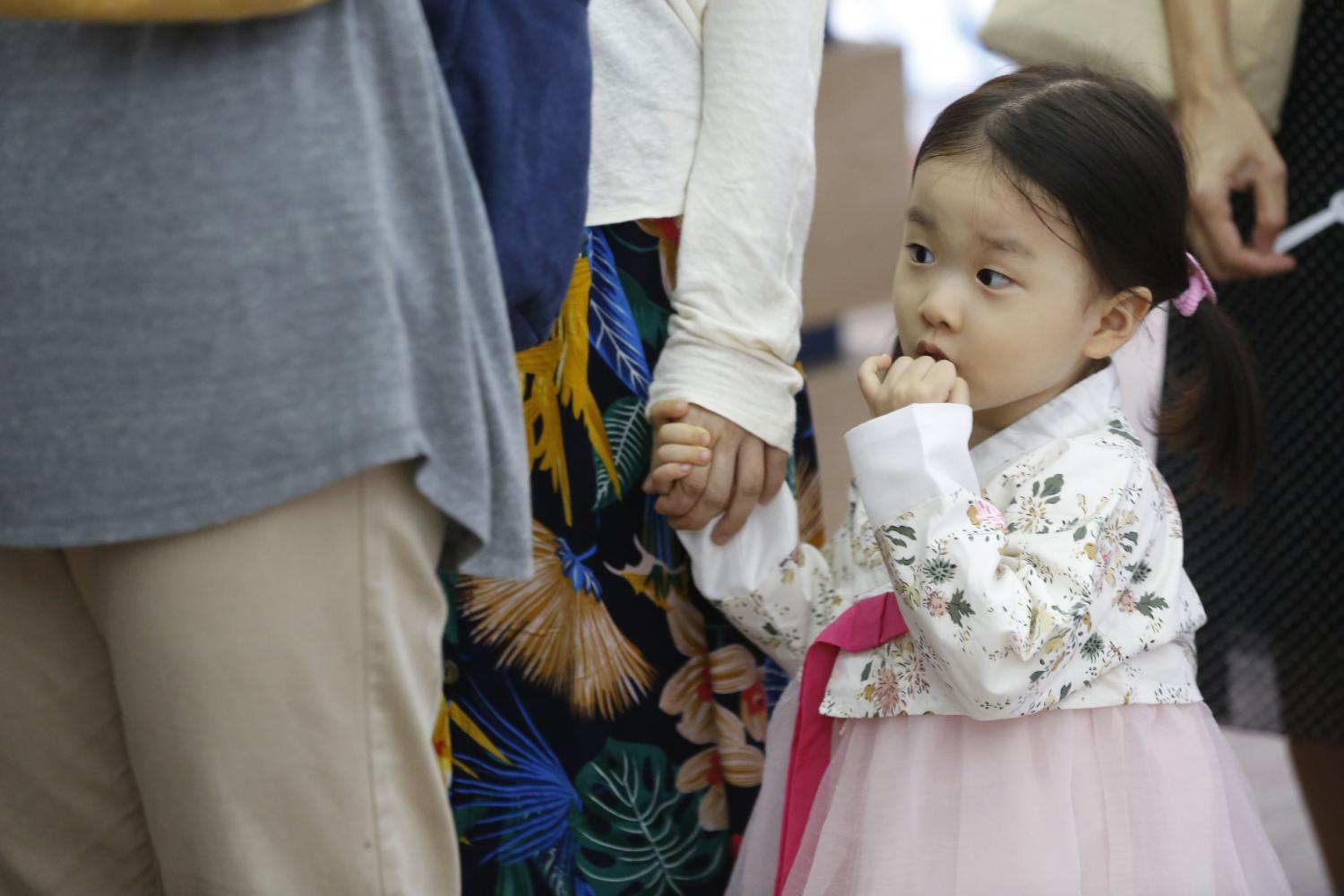 A small girl dressed in traditional Korean Han Bok costume holds a parent's hand as she enjoys an event at the Korean Cultural Centre. (Photos by Pornprom Satrabhaya)