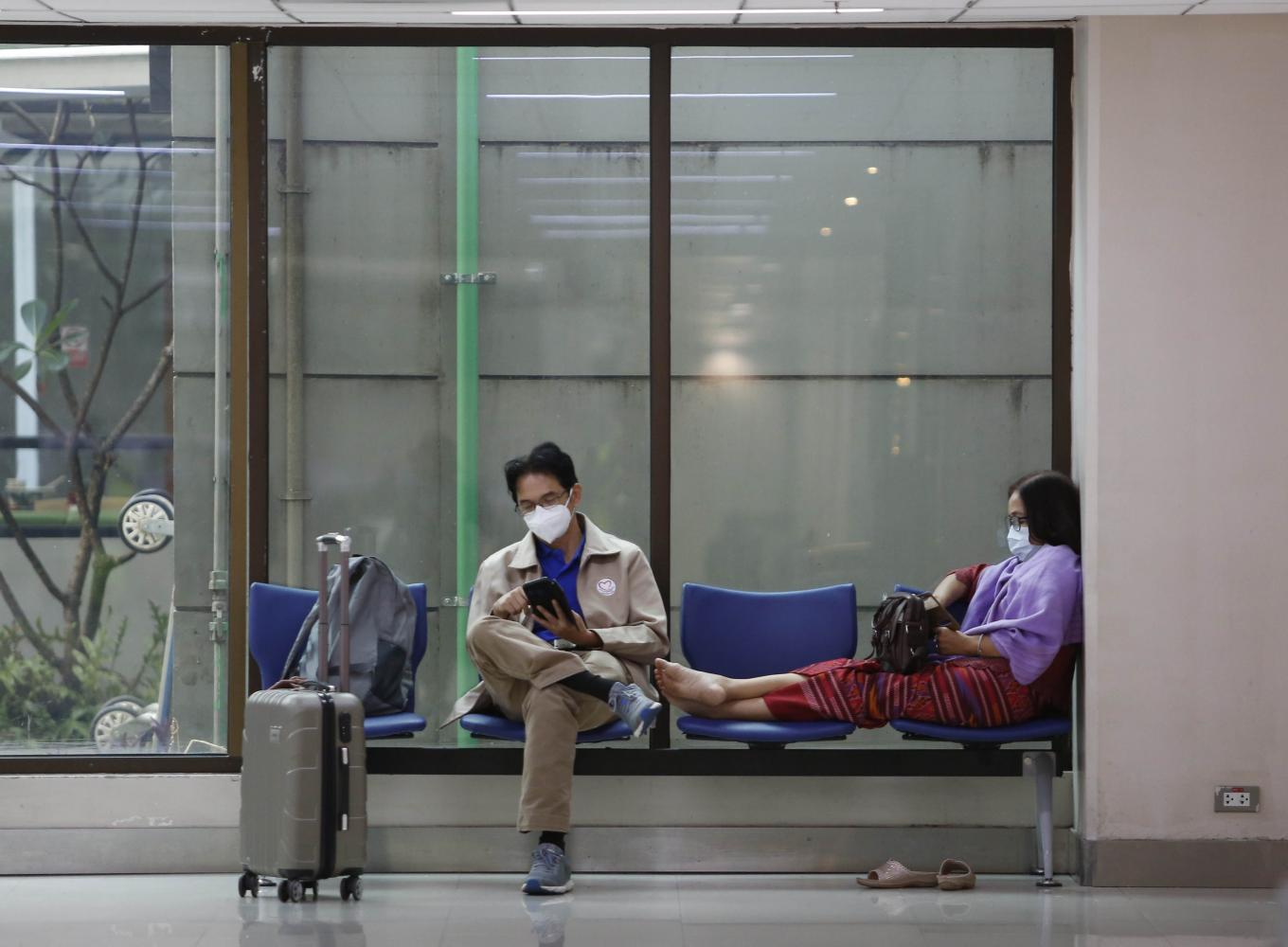 Passengers wearing face masks to protect themselves against the coronavirus wait at a terminal at Don Mueang airport in Bangkok. PATTARAPONG CHATPATTARASILL