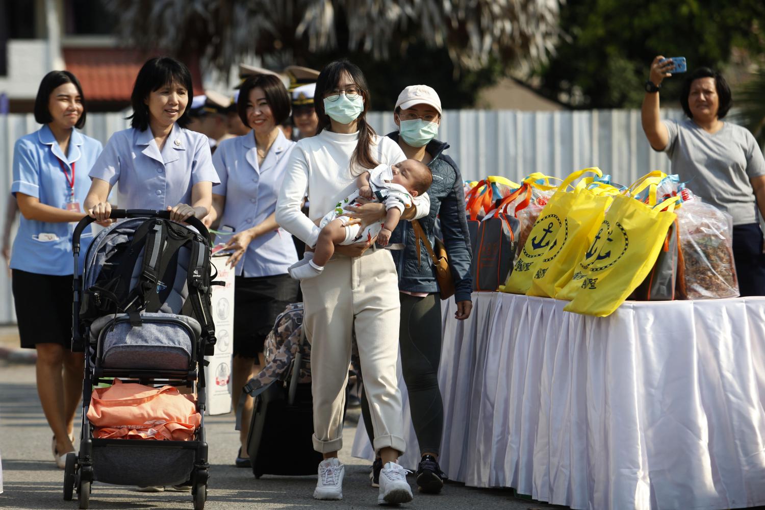 A woman with her baby is assisted by nurses as she leaves the Covid-19 quarantine facility at the naval base in Chon Buri on Wednesday.