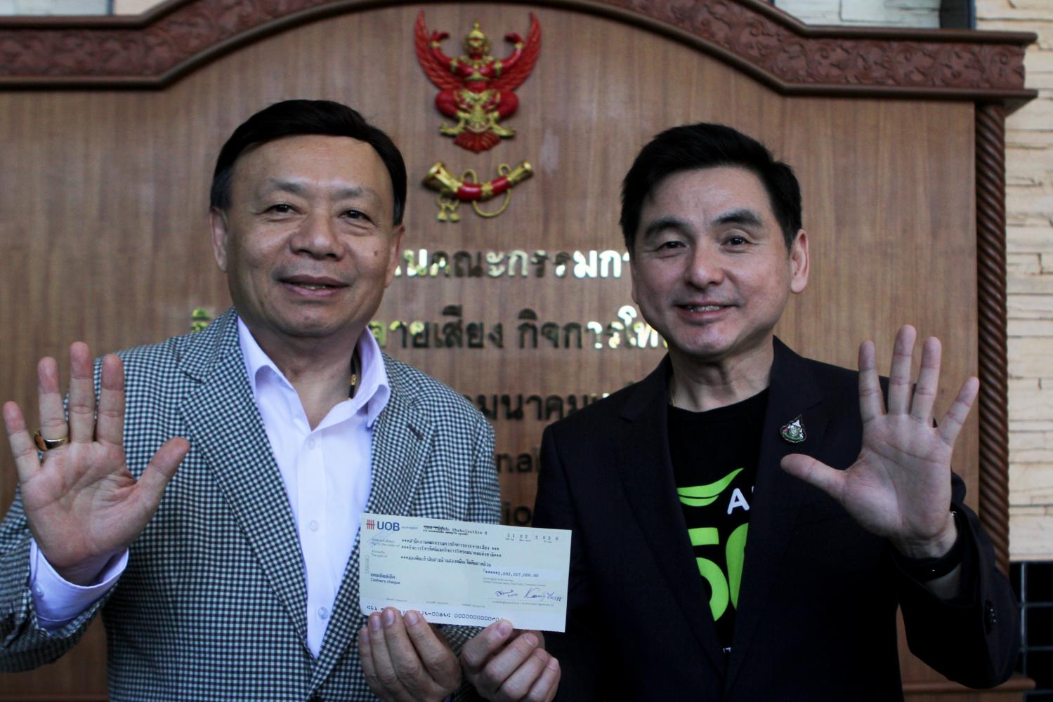 Mr Somchai (right) makes the first instalment payment for 2600MHz spectrum and receives the licence from NBTC secretary-general Takorn Tantasith.