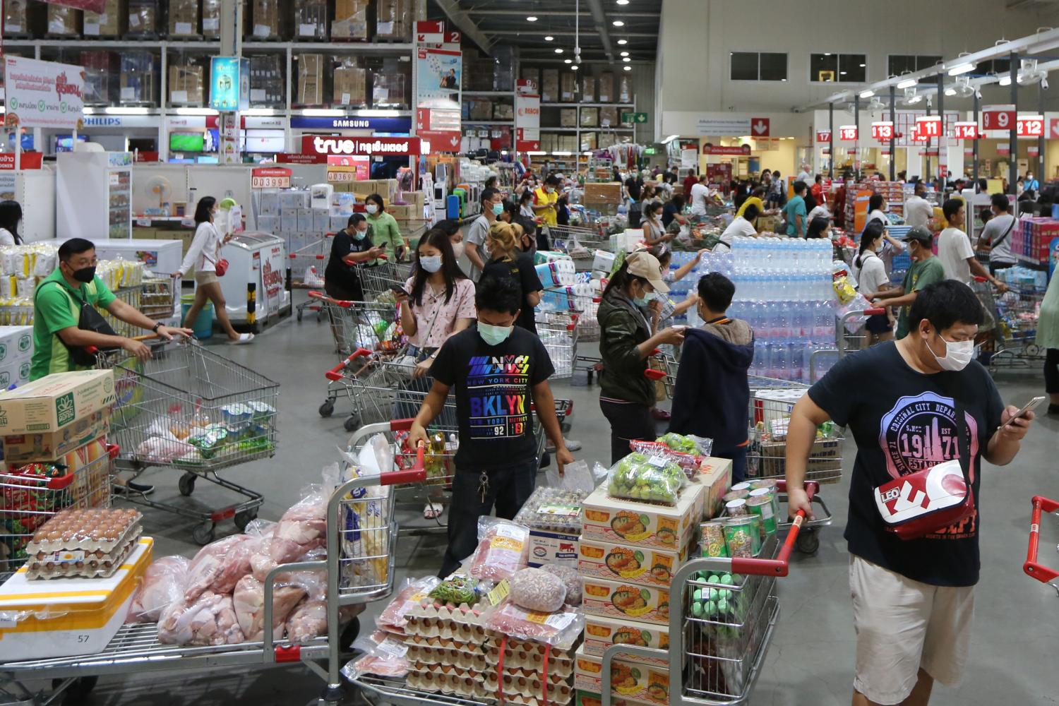 Stocking up: Shoppers form long queues at the Makro wholesale store in Samut Prakan after City Hall yesterday issued an order closing shopping malls and markets in Bangkok and adjacent provinces except those selling food and essential consumer goods for three weeks in an effort to slow the spread of Covid-19.